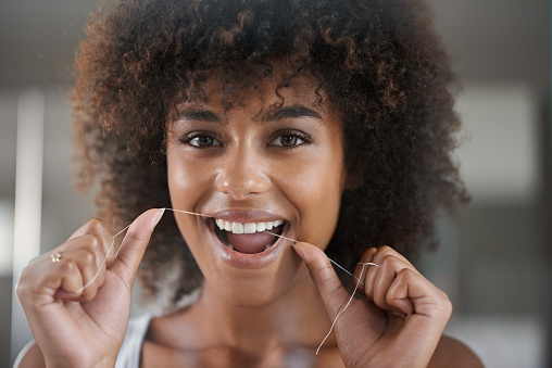 Black woman flossing after appointment at Highridge Dental Care in Folsom, CA