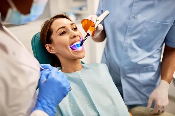 Dentist and assistant performing a dental bonding procedure on a female patient at Highridge Dental Care in Folsom, CA