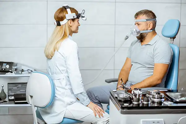 Doctor assesses a patient with a CPAP sleep apnea machine attached to his face at Highridge Dental Care in Folsom, CA